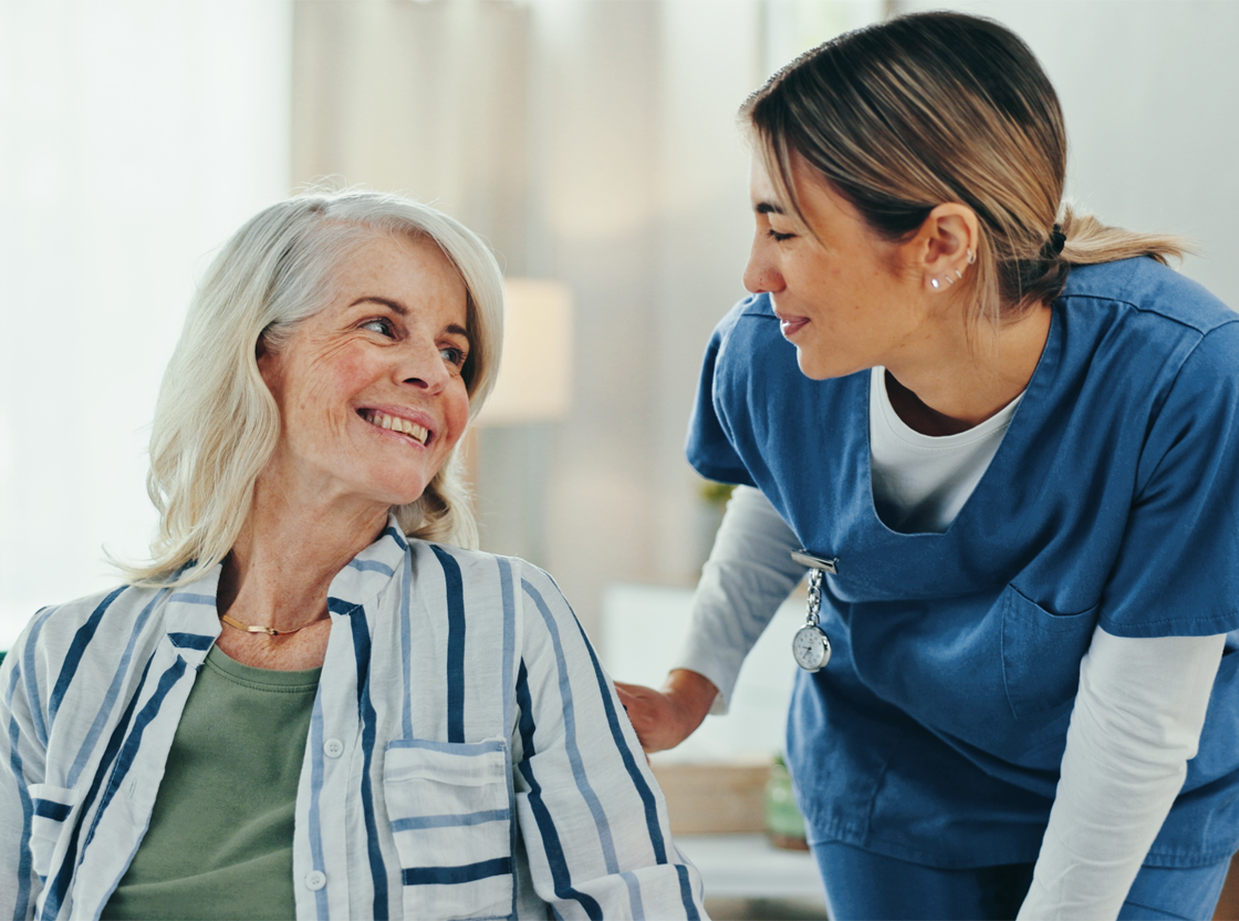 A caregiver interacts with a resident smiling.