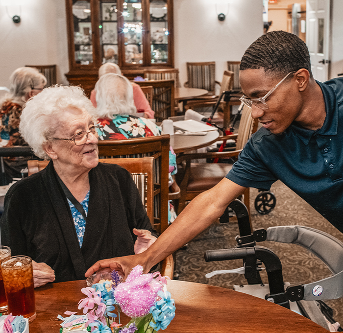 Engaging interaction between staff and resident in a dining area.