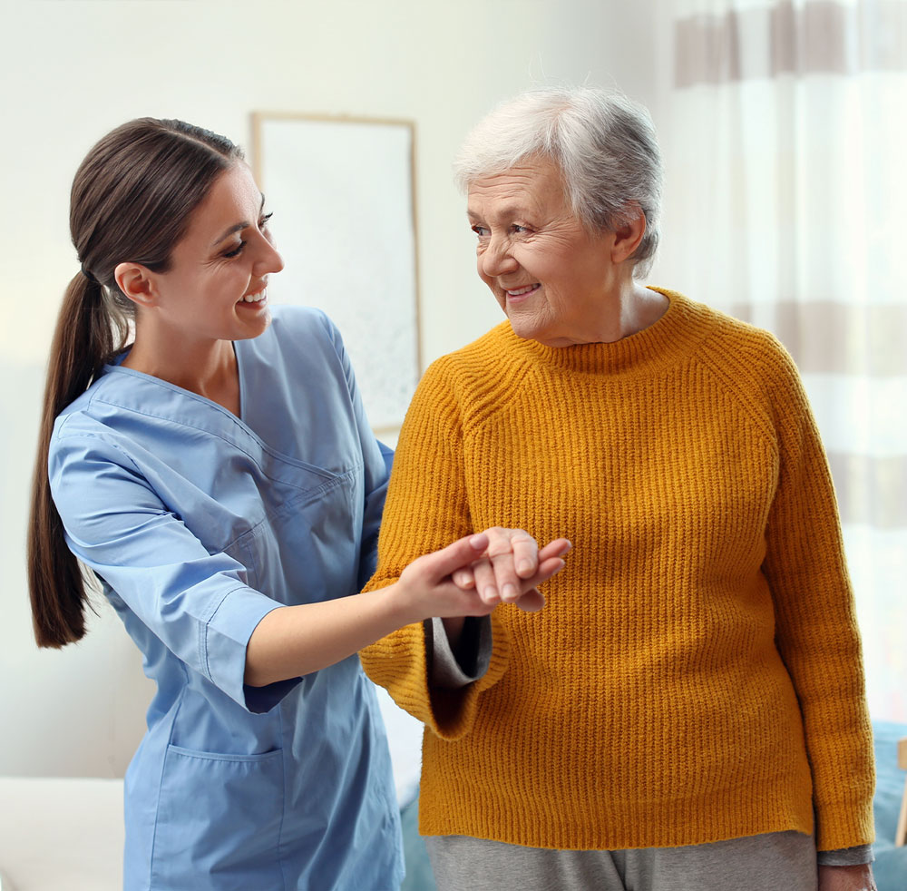 Staff assisting a happy senior resident in a room.