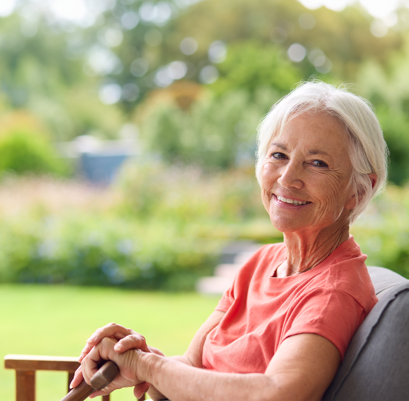 Senior woman smiling in a garden setting.