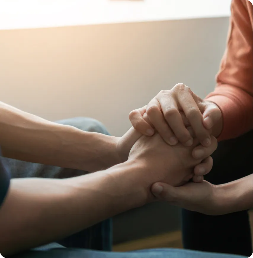 Two people holding hands in a supportive gesture.