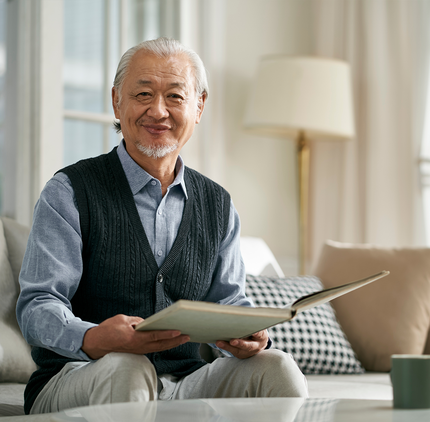 Senior man reading a book in a cozy living room.