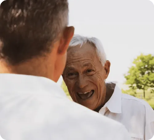 Two elderly men chatting outdoors with smiles.
