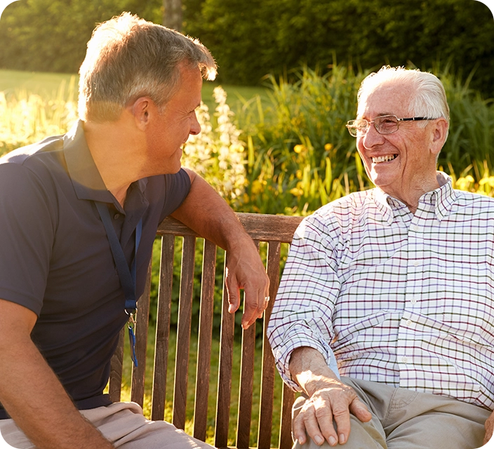 Two men enjoying conversation on a bench outdoors.