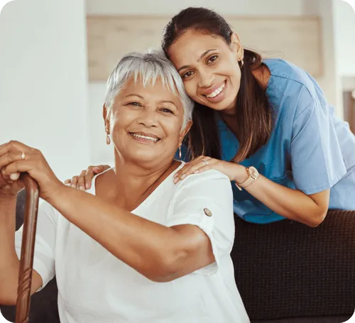 A caregiver and resident smiling in a living area.
