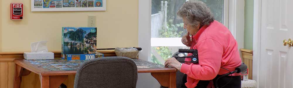 Senior woman working on a puzzle at a table.