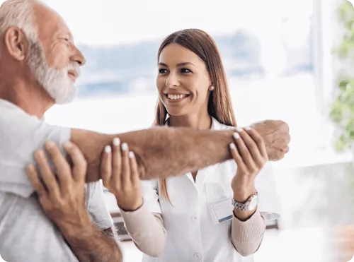 Caregiver assisting an elderly man with a smile.