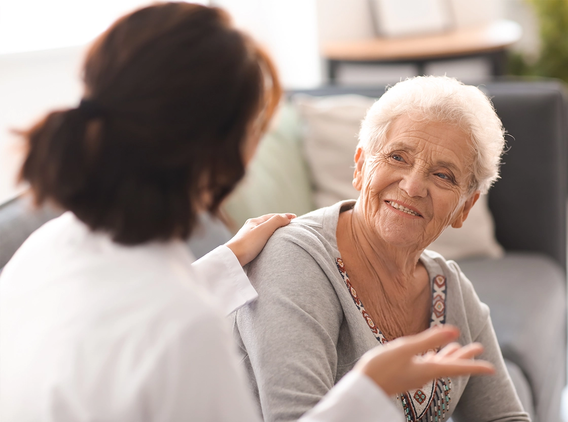 Caregiver interacting with a smiling elderly resident.