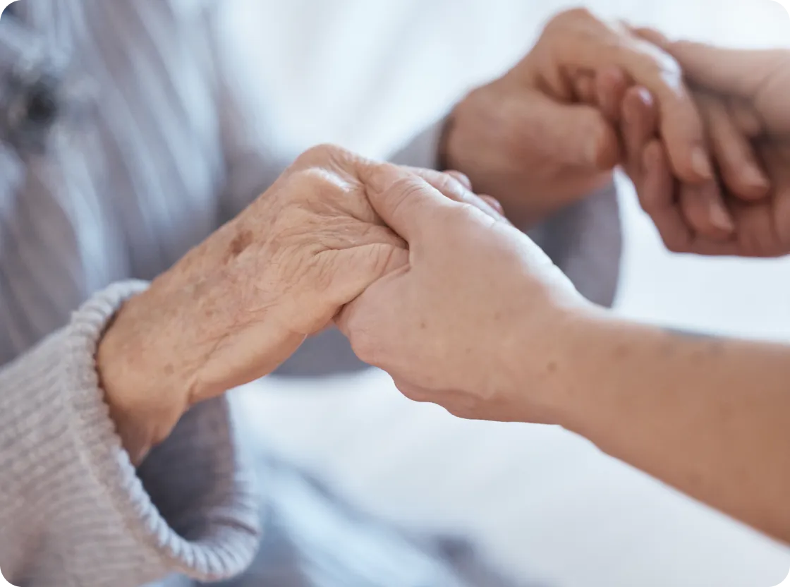 Hands of a caregiver and a senior holding each other