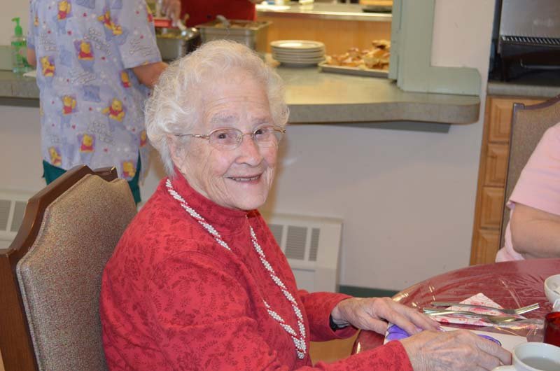Elderly woman smiling in a dining area