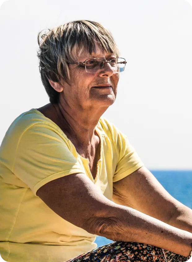 Senior woman sitting outdoors in thoughtful pose.