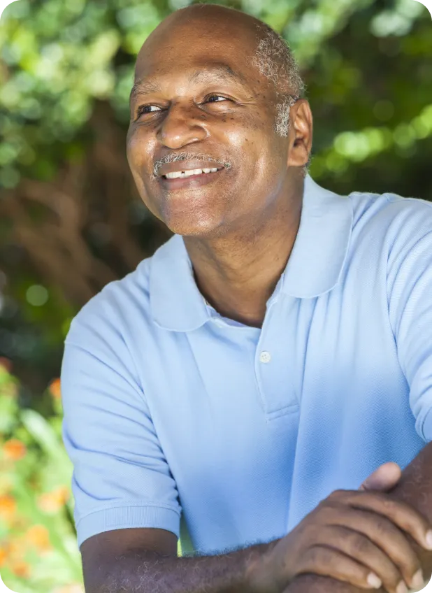 Smiling senior man outdoors in a garden setting.