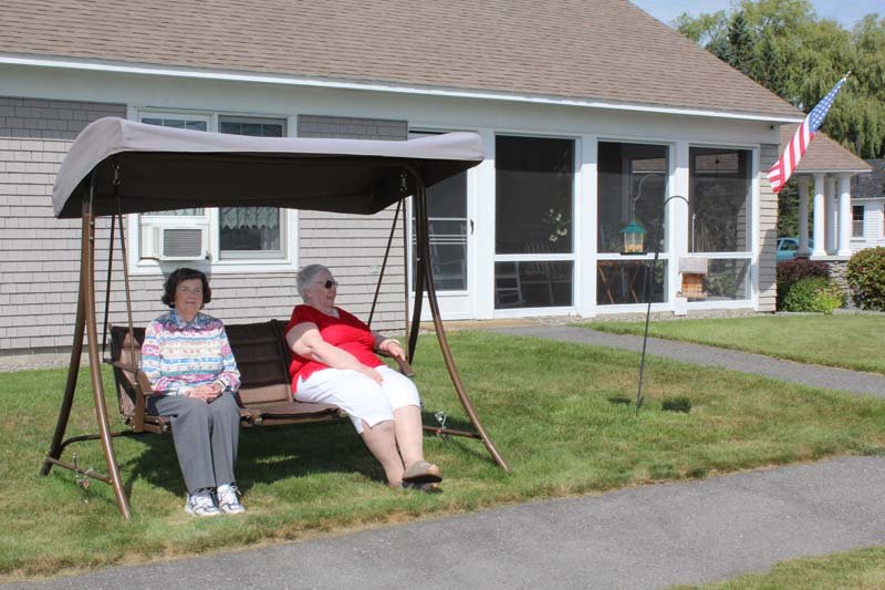 Two residents relaxing on a swing outside.