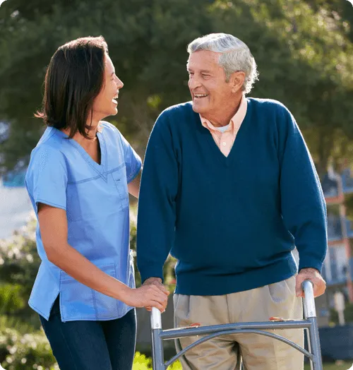 Caregiver assisting an elderly man outdoors