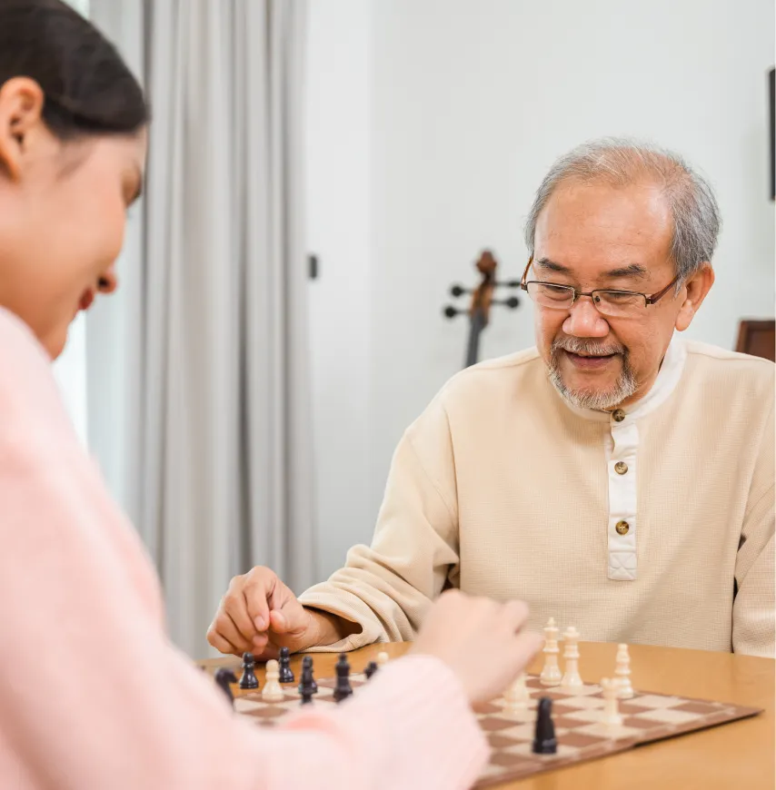 Senior resident playing chess with a caregiver.