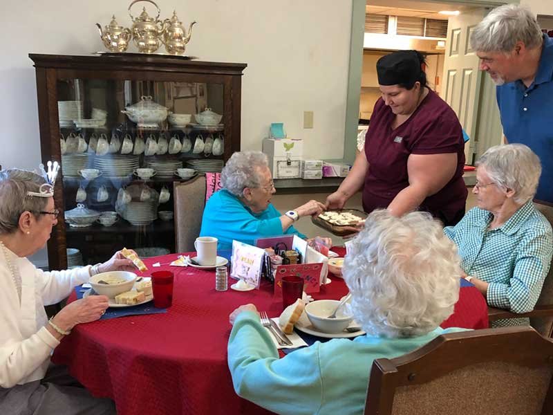 Residents enjoying a meal together with staff assistance.