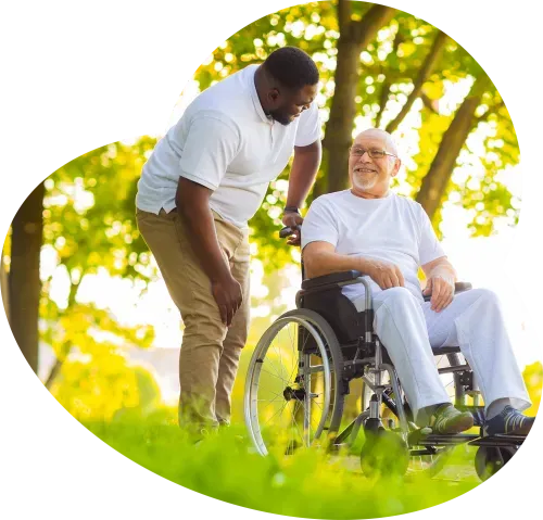 Caregiver assisting senior in a wheelchair outdoors.
