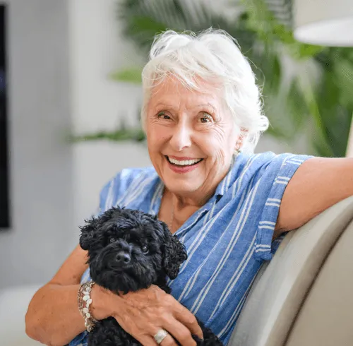 Smiling senior woman holding a dog in a common area