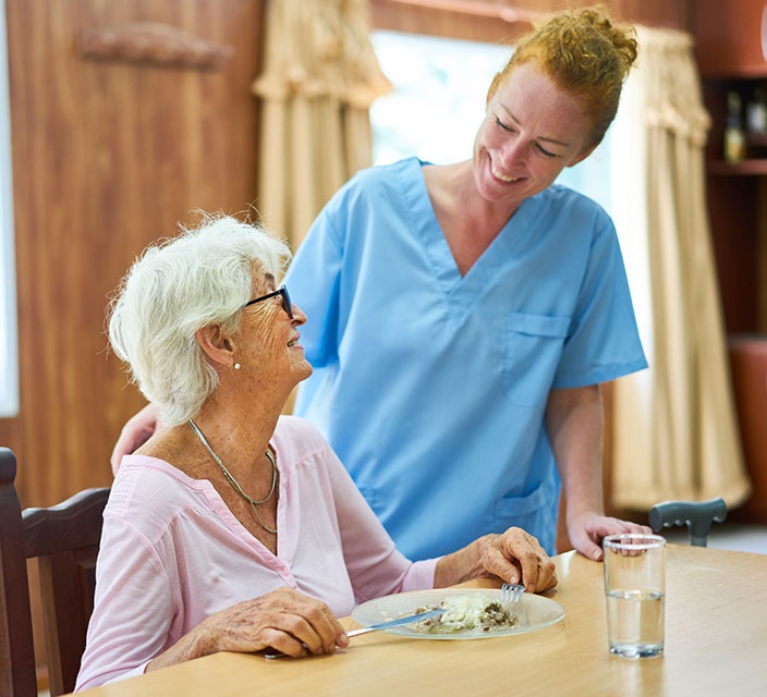 Staff interacting with a resident during meal time.