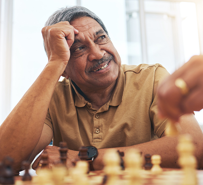 A smiling man playing chess in a common area.