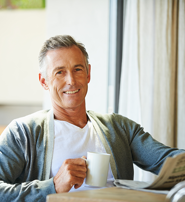 Smiling senior man enjoying coffee and reading