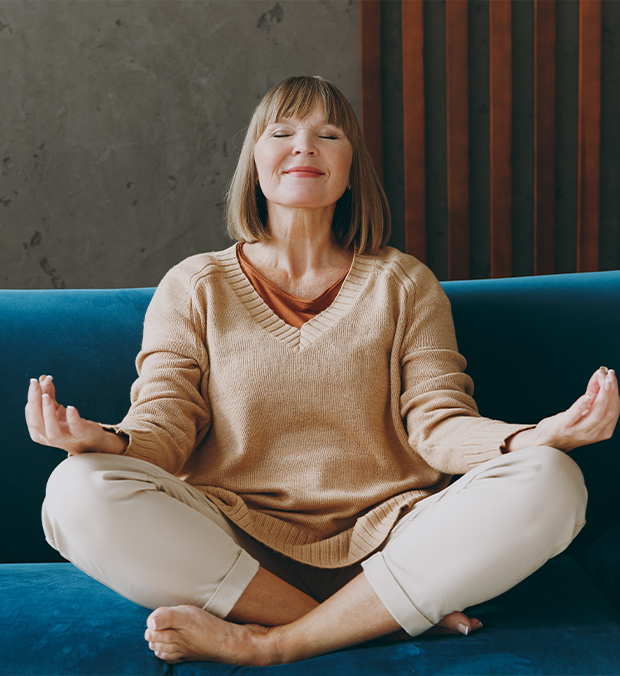 Woman meditating on a couch in a serene environment.