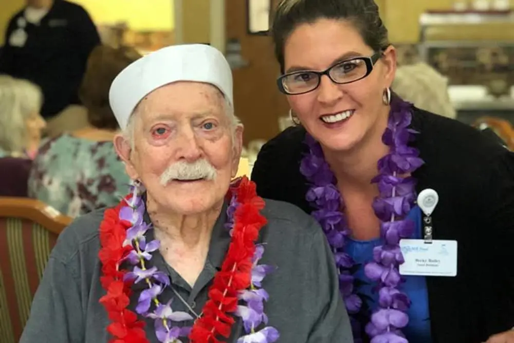 Senior resident and staff member celebrating together.