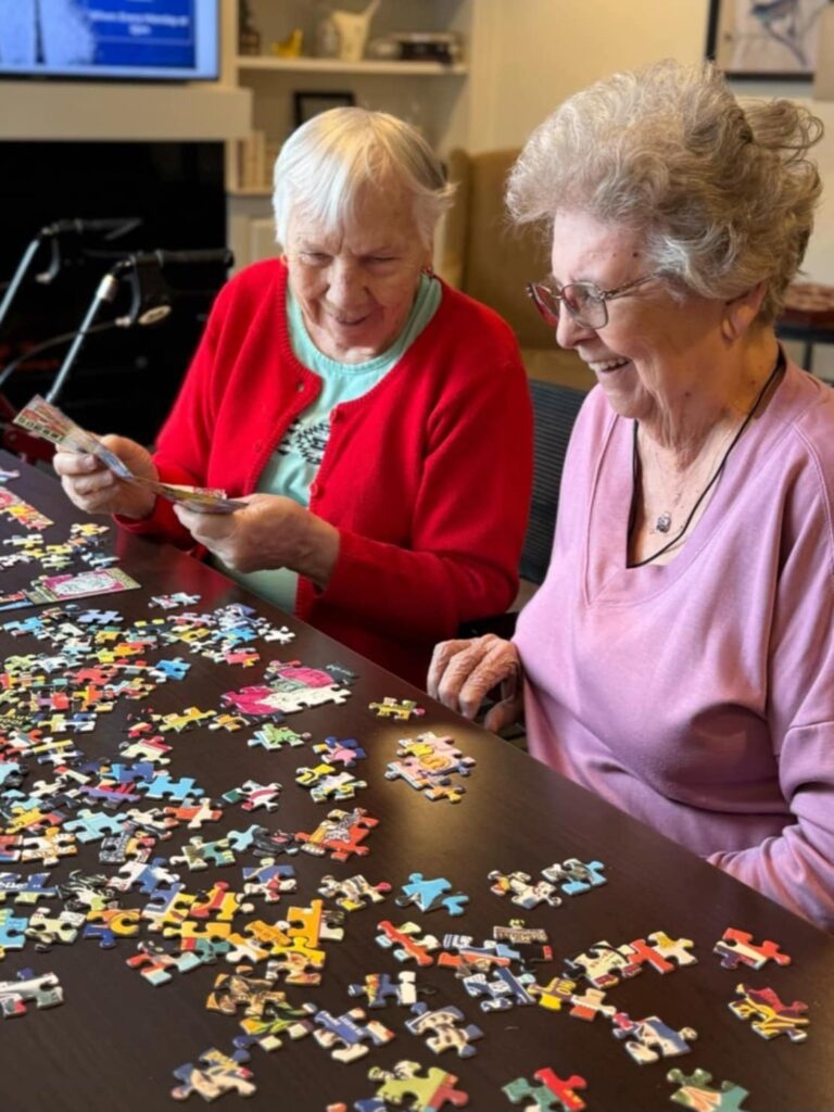 Two senior women working on a jigsaw puzzle together.
