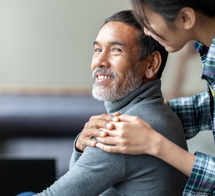 Caregiver interacting with elderly man indoors.