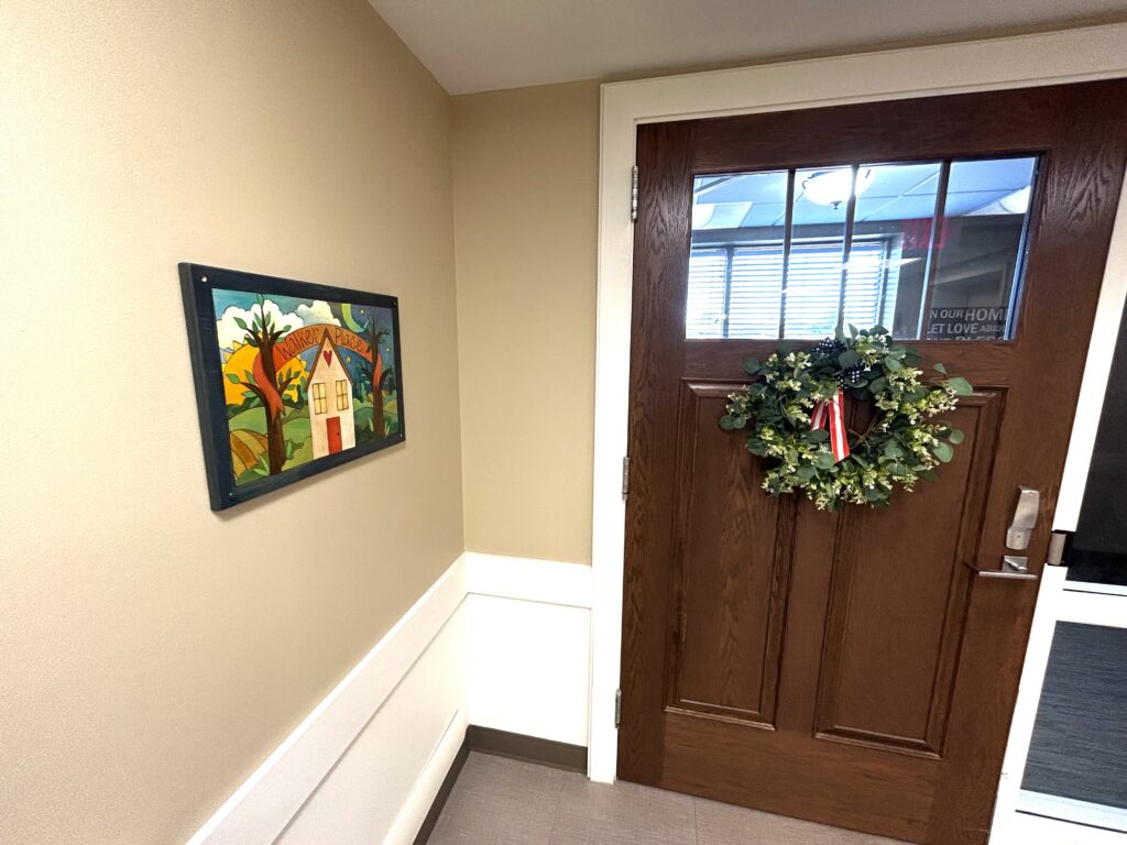 Decorative wall outside a door with greenery.