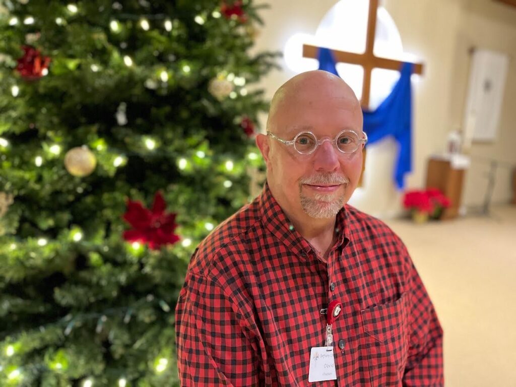 Resident posing in front of a Christmas tree.