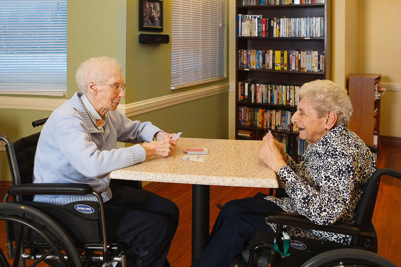 Two elderly women playing cards in a common area
