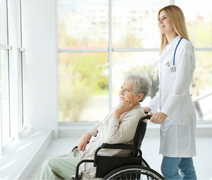Nurse assisting an elderly woman in a wheelchair