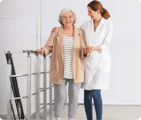 A caregiver assists an elderly woman in a hallway.