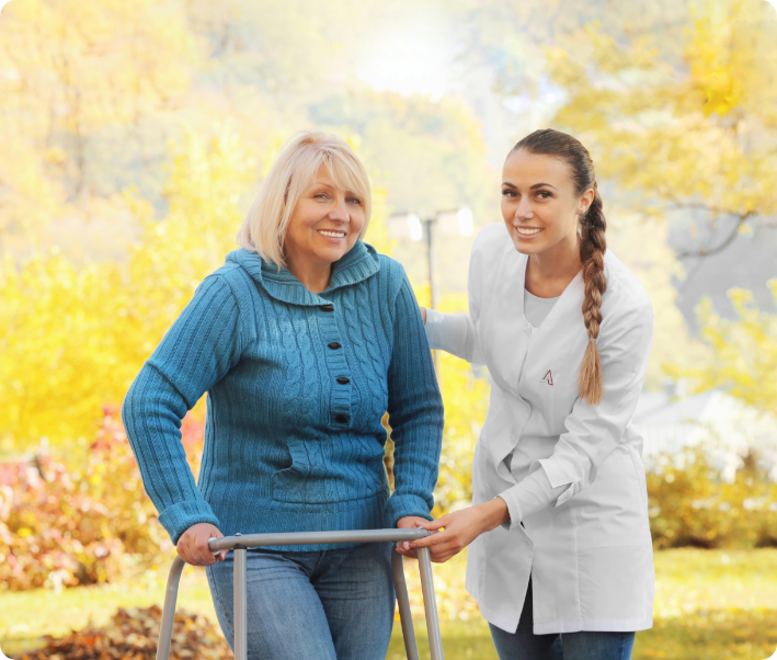 Staff assisting a resident outdoors with a walker.