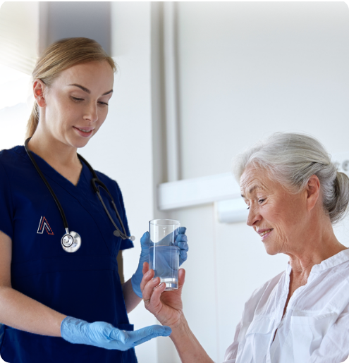 Nurse assisting senior resident with a glass of water.