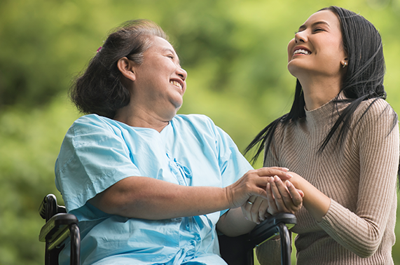Resident and caregiver smiling together outdoors.