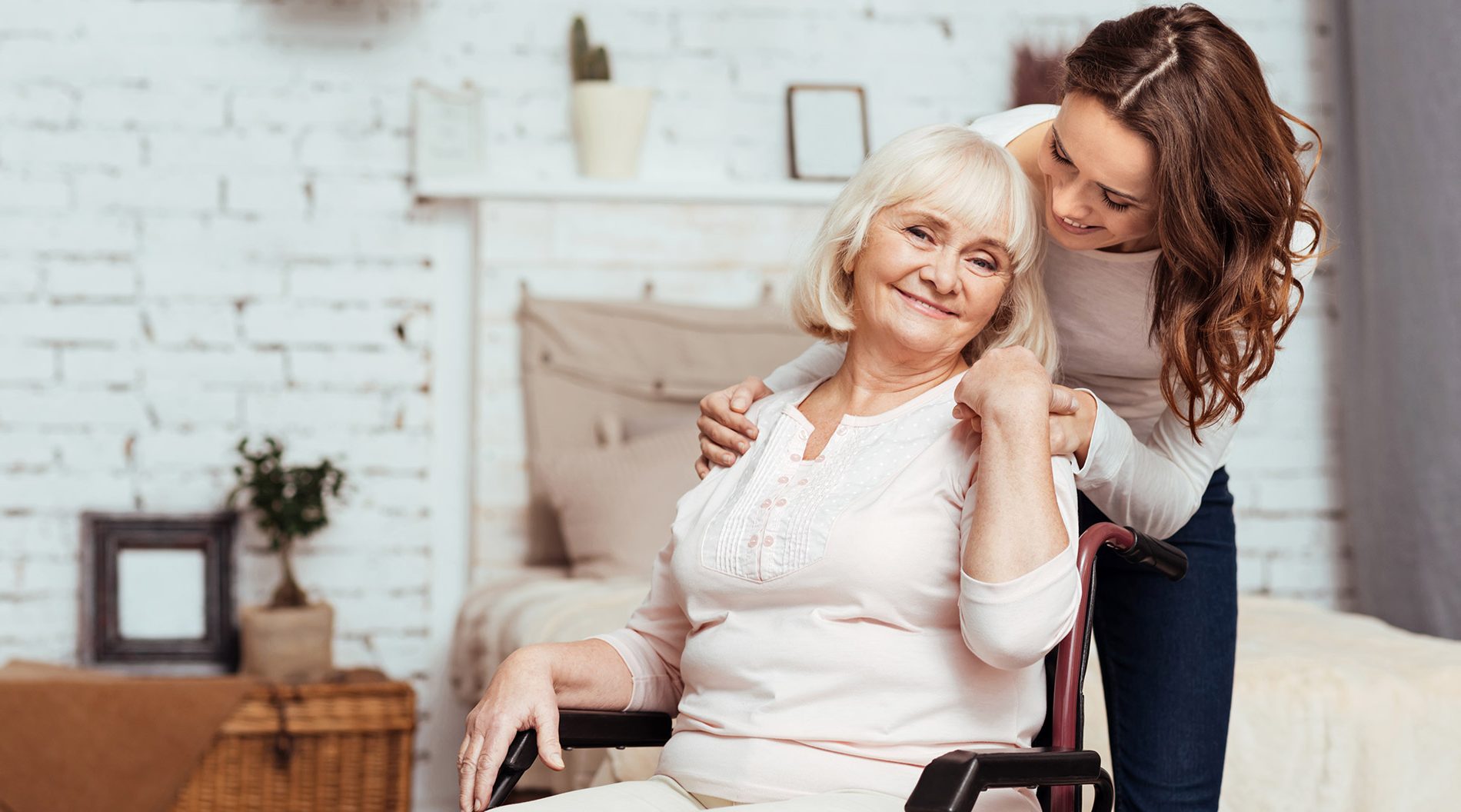 Caregiver assisting elderly woman in a cozy room