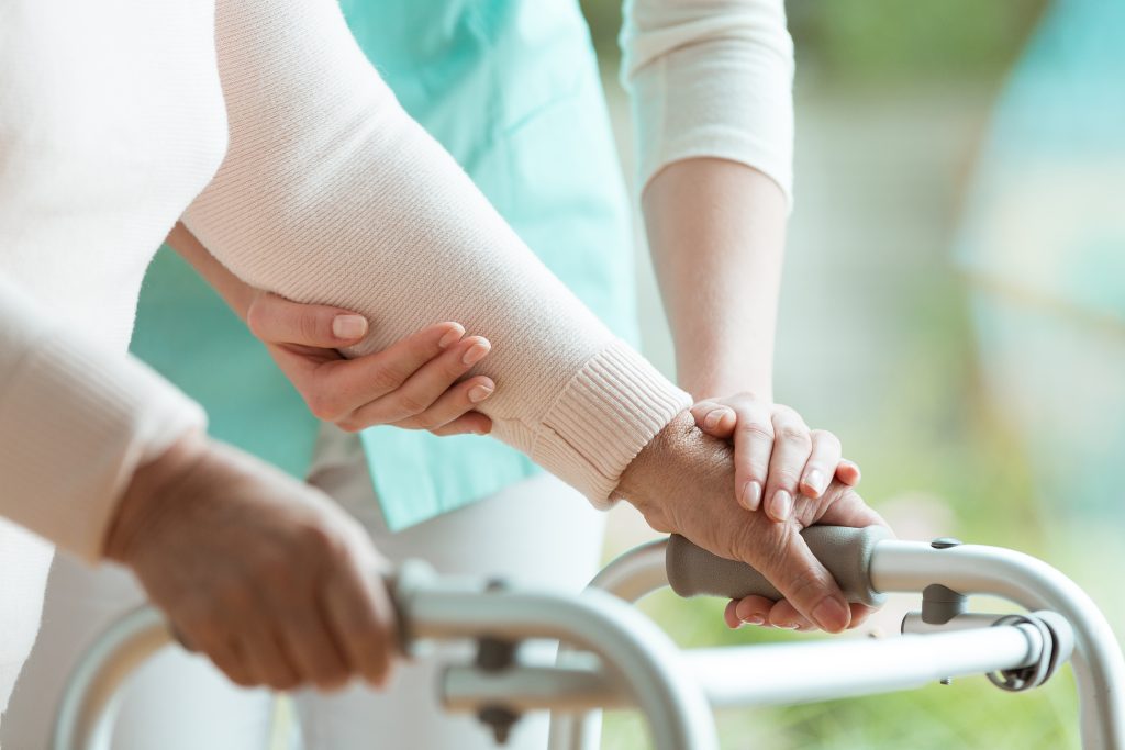 Caregiver assisting a resident with a walker.
