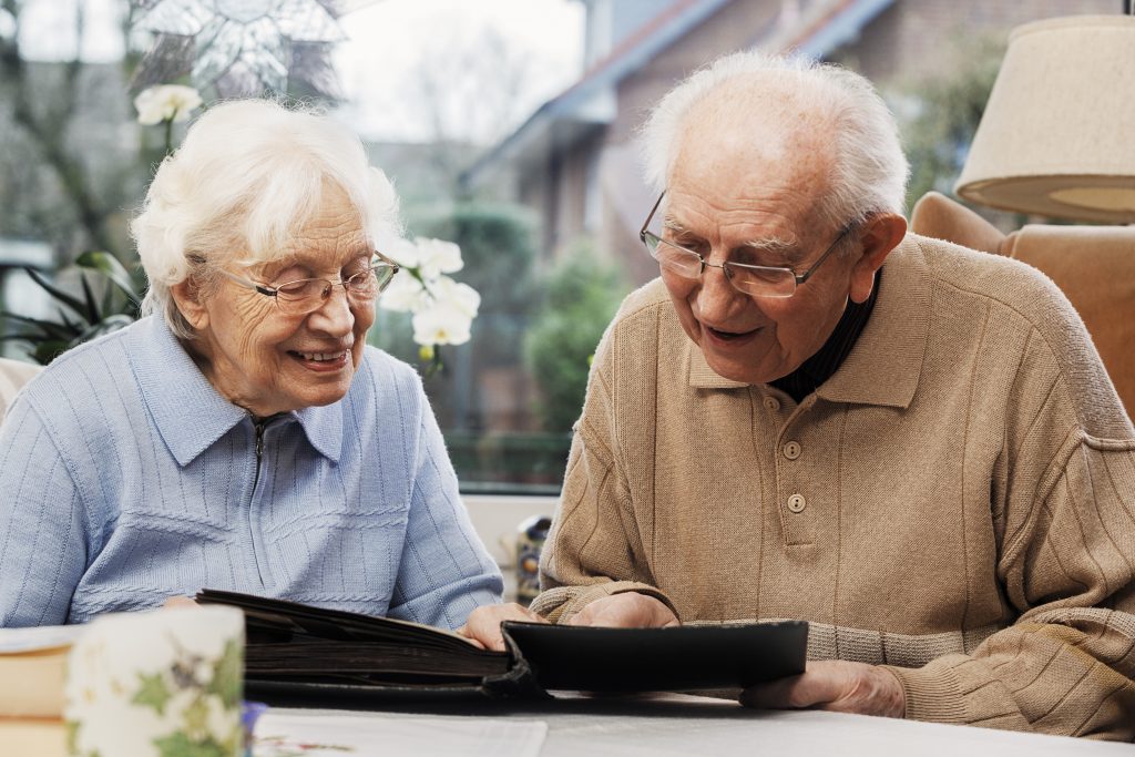 Two seniors enjoying a photo album together indoors.
