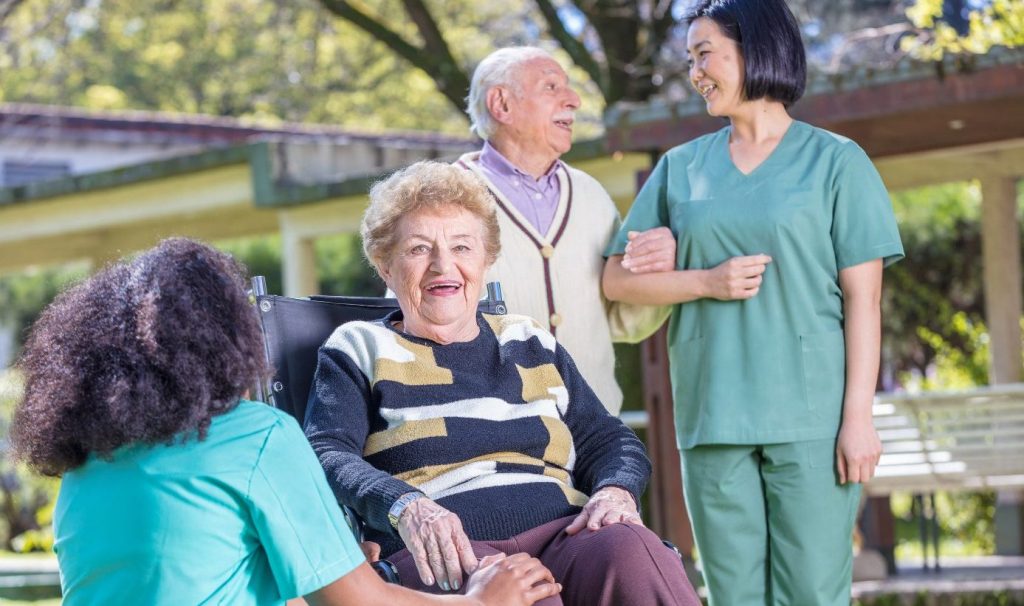 Residents and staff interacting outdoors in a sunny setting.