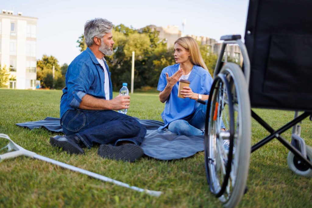 Two people having a conversation outdoors on grass.