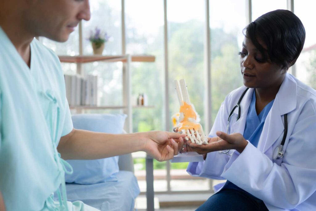Doctor explaining a model of a foot to a patient.