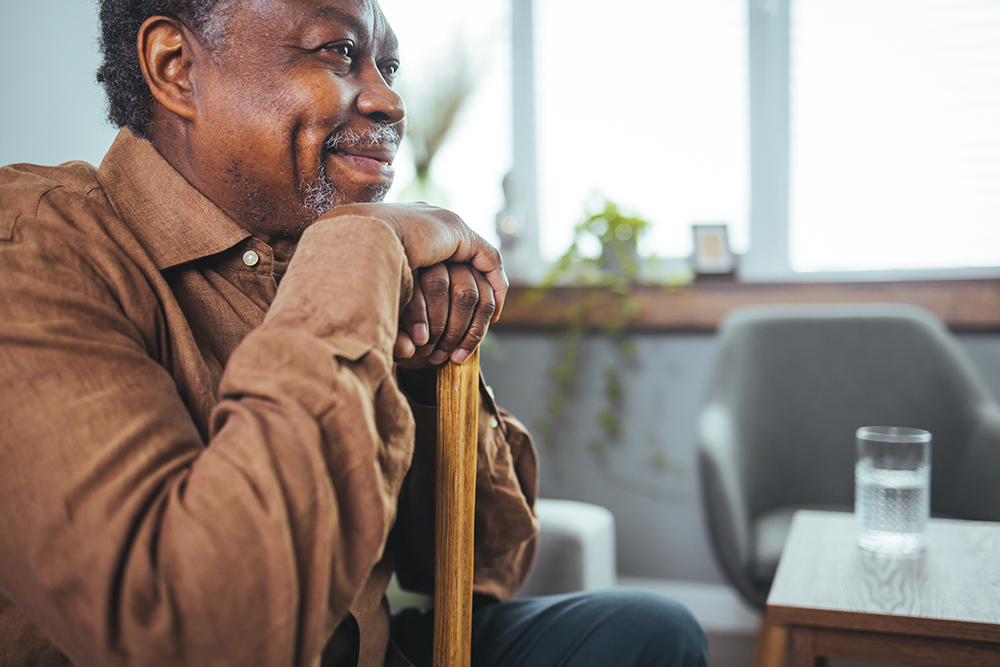 Senior man smiling while resting on a chair.