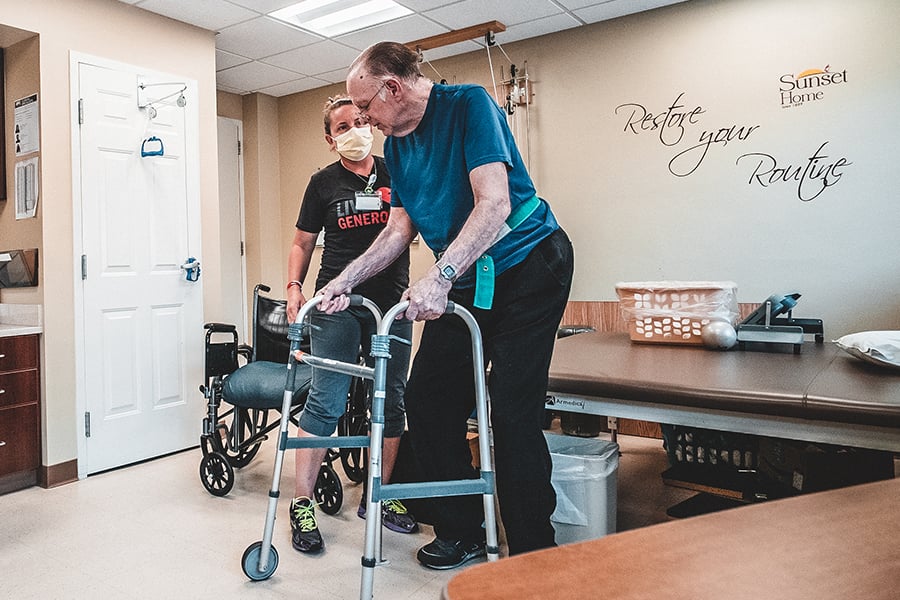 Senior resident assisted by staff in therapy room