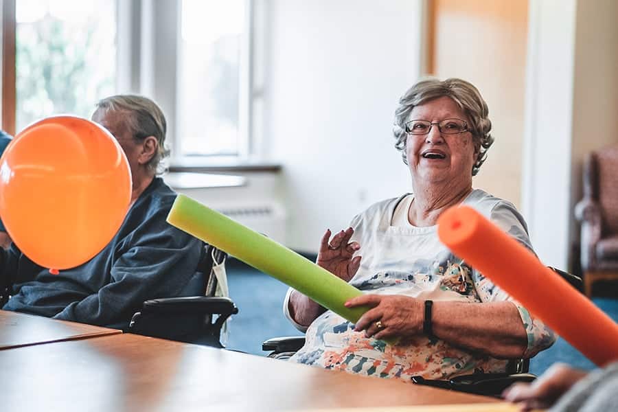 Residents engaging in a playful activity with balloons and foam noodles.