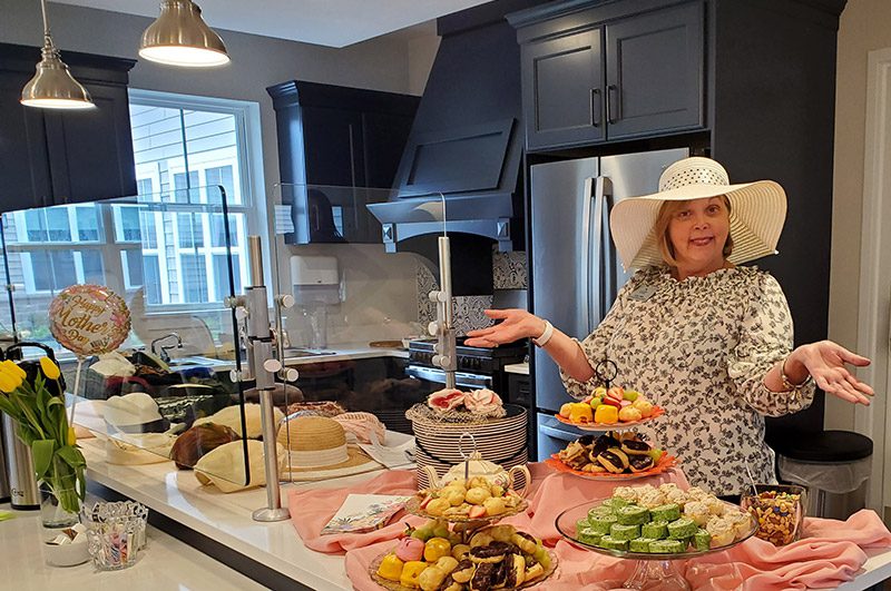A woman presenting a variety of beautifully arranged food.
