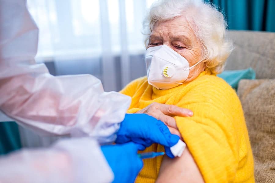Older woman receiving a vaccine in a care setting.