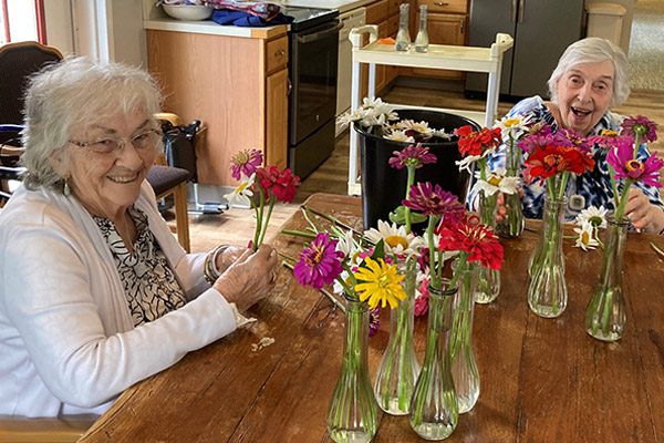 Two residents arranging flowers at a table