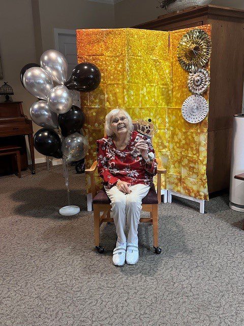 Resident celebrating with balloons in a decorated area.